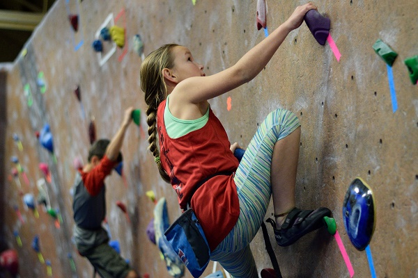 Young girl bouldering on an indoor bouldering wall in Roanoke, Virginia