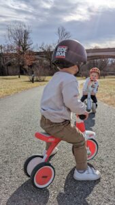 Two young children on tricycles on a greenway path.